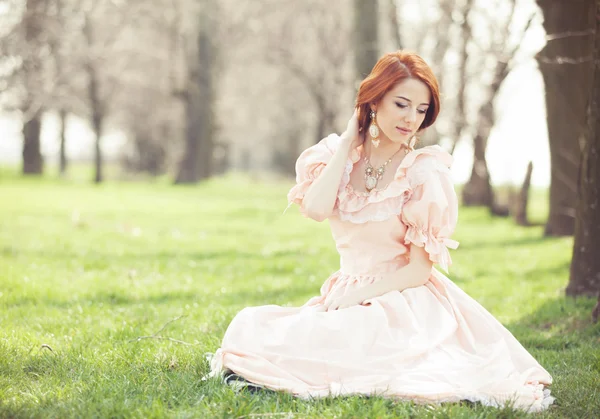 Mooie vrouwen in jurk zittend op een voorjaar gras. — Stockfoto