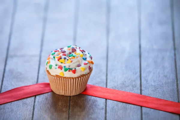 Cupcake och rosett på träbord. — Stockfoto