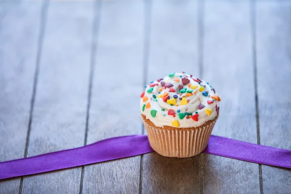 Cupcake e fiocco sul tavolo di legno . — Foto Stock