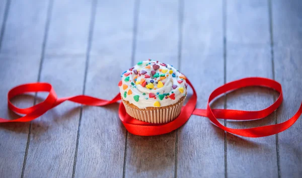 Cupcake e arco na mesa de madeira . — Fotografia de Stock