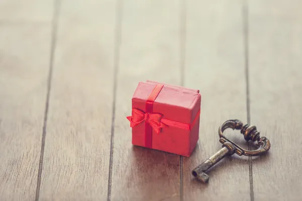 Retro anahtar ve ahşap masa üzerinde küçük kırmızı hediye. — Stok fotoğraf