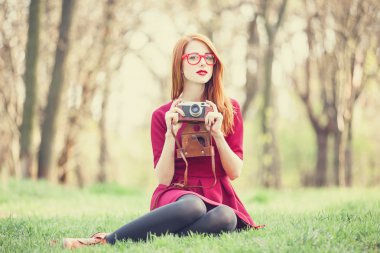 Kızıl saçlı kadın kamera ile bir parkta