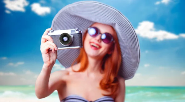 Rothaarige Mädchen mit Retro-Kamera am Strand — Stockfoto