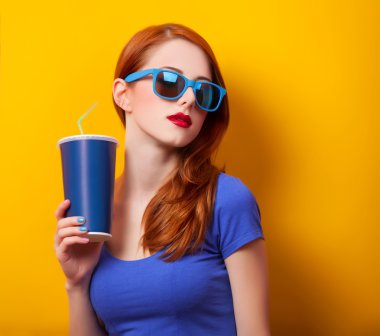 Kızıl saçlı kız içki ve Sarı zemin üzerine güneş gözlüğü