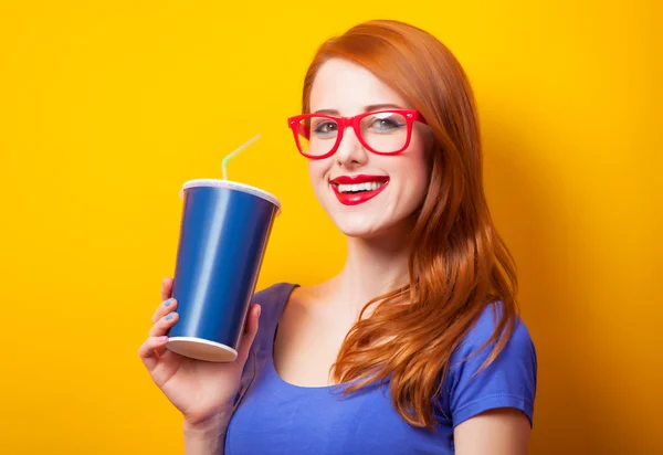 Pelirroja con bebida y gafas sobre fondo amarillo . —  Fotos de Stock