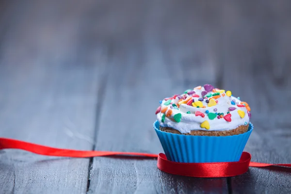 Cupcake and bow on wooden table. — Stock Photo, Image