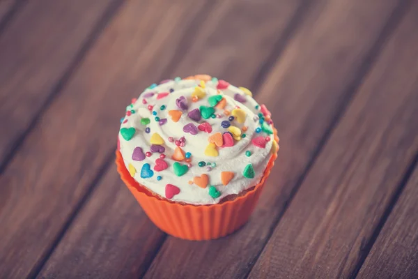 Cupcake e arco na mesa de madeira . — Fotografia de Stock