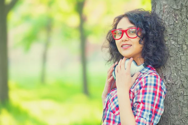 Indiase meisje met koptelefoon in het park. — Stockfoto