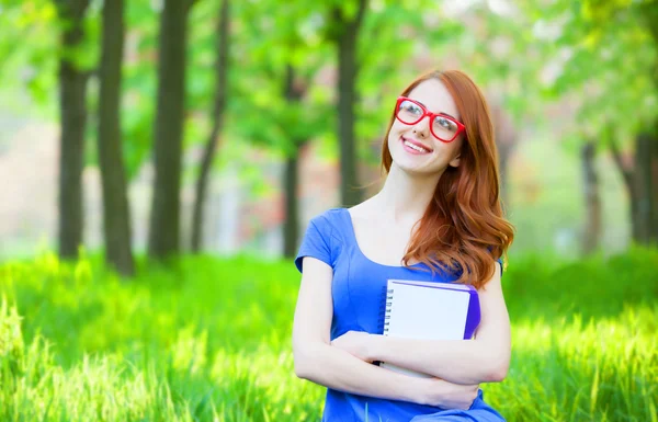 Портрет молодой рыжей улыбчивой женщины в очках и с заметкой — стоковое фото
