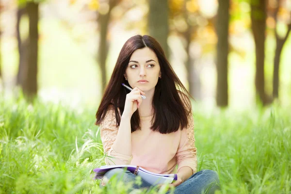 Brunetka dziewczynka z notebooka w parku. — Zdjęcie stockowe