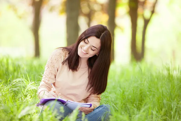 Brunetka dziewczynka z notebooka w parku. — Zdjęcie stockowe