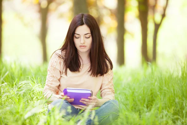 Brunetka dziewczynka z notebooka w parku. — Zdjęcie stockowe