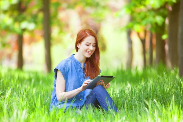 Redhead girl with talet in the park — Stock Photo, Image