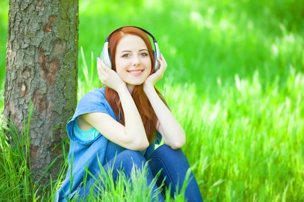 Donne rosse con le cuffie nel parco . — Foto Stock