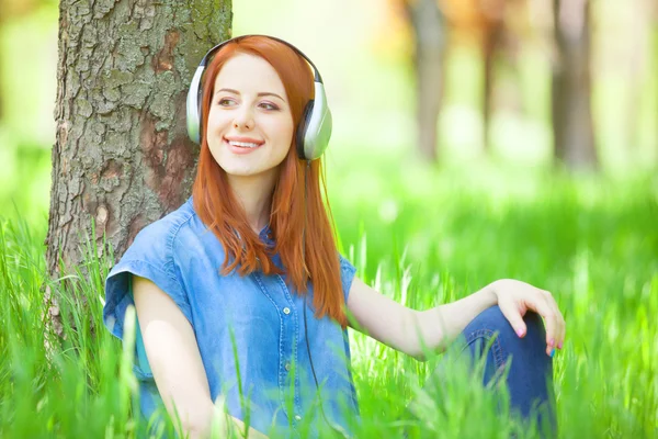 Γυναίκες κοκκινομάλλα με ακουστικά στο πάρκο. — Φωτογραφία Αρχείου