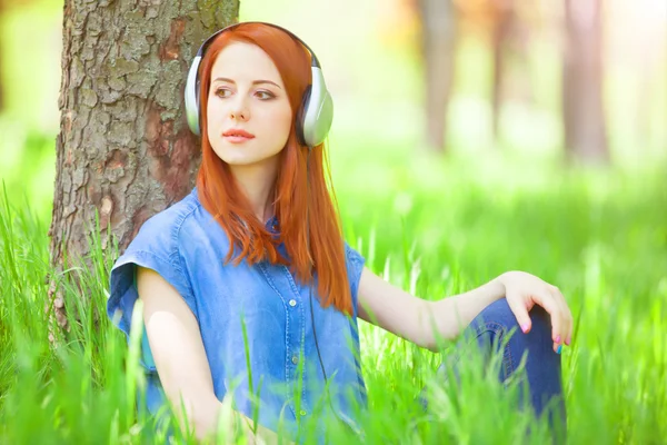 Kızıl saçlı kadın parkta kulaklıklarla. — Stok fotoğraf