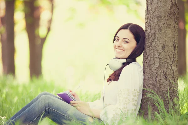 Brunetka dziewczynka z notebooka w parku. — Zdjęcie stockowe