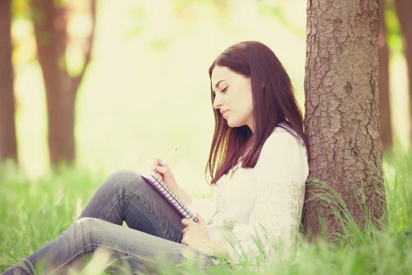 Brunetka dziewczynka z notebooka w parku. — Zdjęcie stockowe