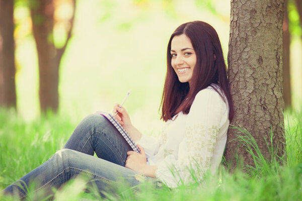 Brunette girl with notebook in the park.