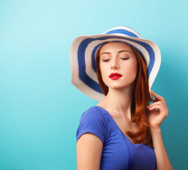 Kızıl saçlı kız mavi zemin üzerine şapkalı.