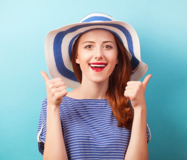 Kızıl saçlı kız mavi zemin üzerine şapkalı.