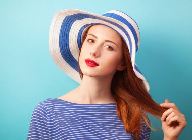 Kızıl saçlı kız mavi zemin üzerine şapkalı.