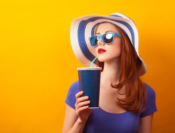 Pelirroja con bebida y gafas de sol sobre fondo amarillo —  Fotos de Stock