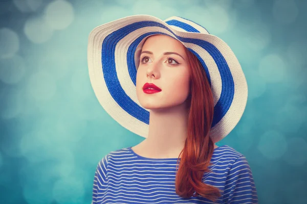 Рыжая девушка в шляпе на синем фоне . — стоковое фото