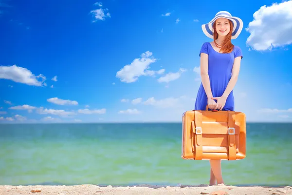 Roodharige meisje met koffer op het strand in de lentetijd. — Stockfoto
