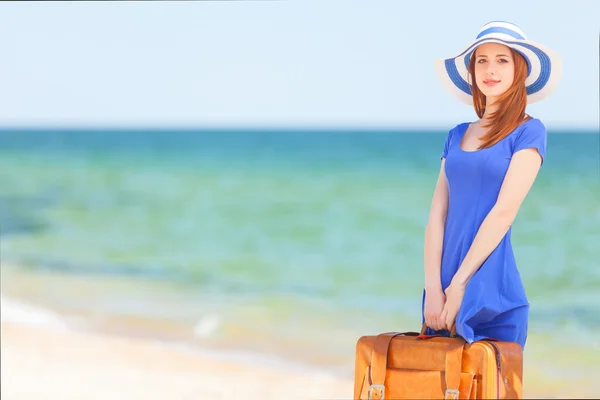 Rödhårig tjej med resväska på stranden i vår tid. — Stockfoto