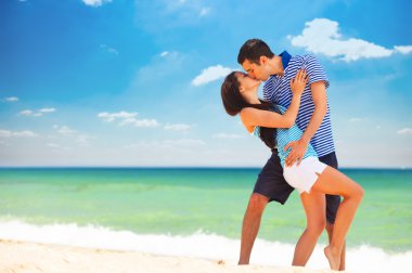 jovem casal beijando na praia em dia de verãogenç bir çift sahilde yaz günü öpüşme.