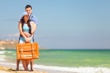 Yaz günü sahilde bavullu genç bir çift..