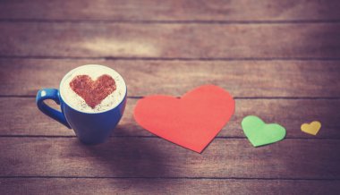 ahşap masa kahve ve kalp şekli kağıtlara fincanla.