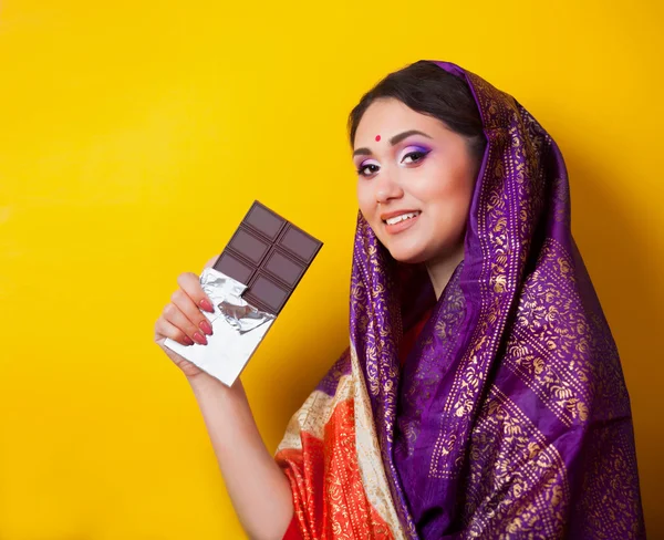 Chica india con chocolate sobre fondo amarillo . —  Fotos de Stock