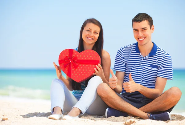 Jovem casal com presente na praia no dia de verão . — Fotografia de Stock