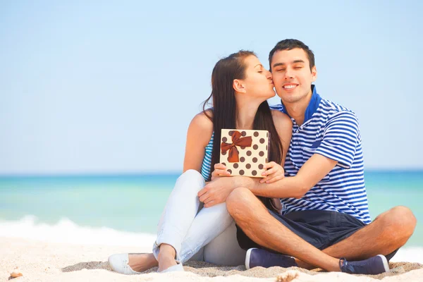 Junges Paar mit Geschenk am Strand im Sommertag. — Stockfoto