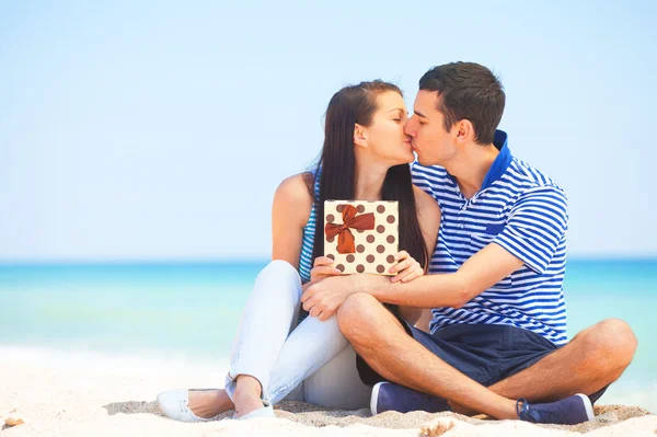 Jovem casal com presente na praia no dia de verão . — Fotografia de Stock