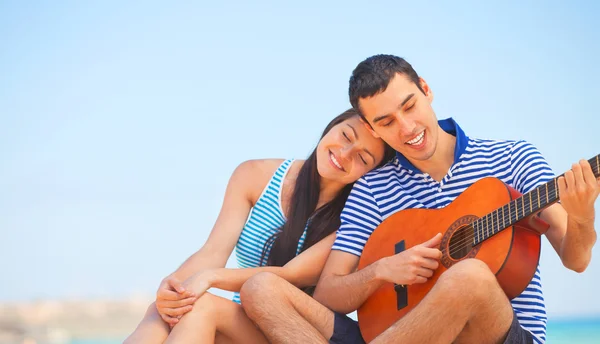 Young couple with guitar on the beach in summer day. — Stock Photo, Image