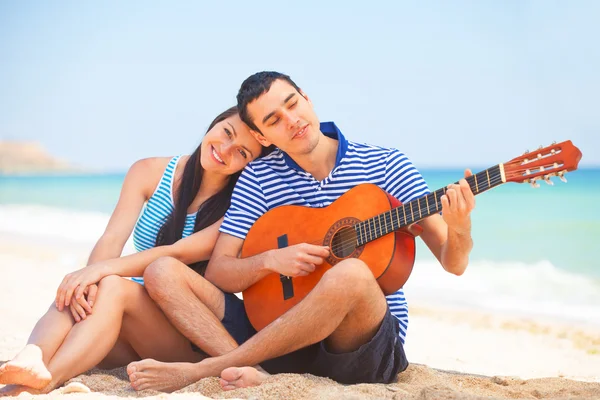 Young couple with guitar on the beach in summer day. — Stock Photo, Image