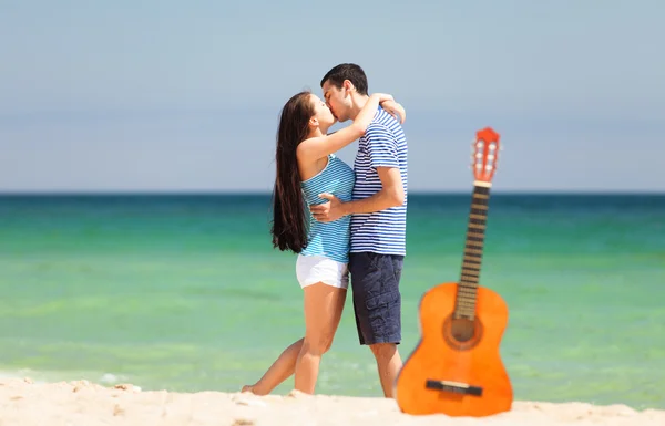 Pareja joven con guitarra en la playa en el día de verano . — Foto de Stock