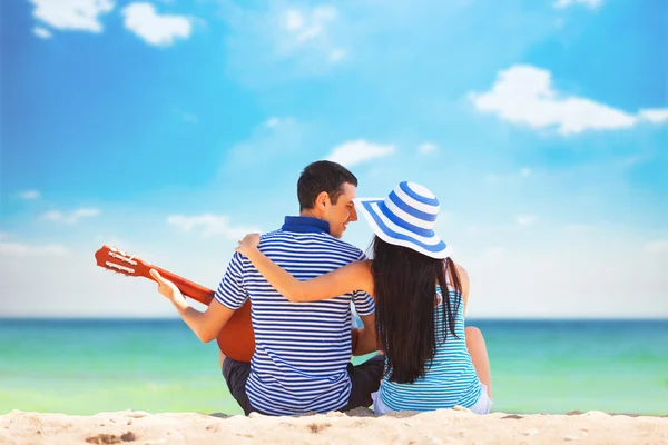 Young couple with guitar on the beach in summer day — Stock Photo, Image