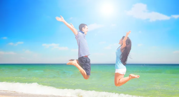 Young couple jumping on the beach in summer day. — Stock Photo, Image