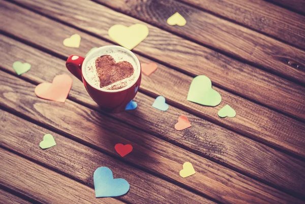 Taza con papel de café y corazón sobre mesa de madera . — Foto de Stock