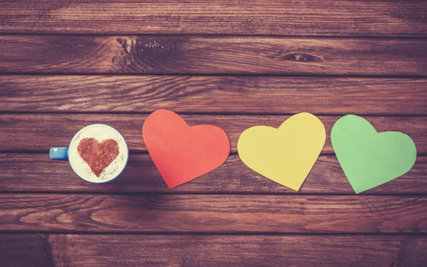 Cup with coffee and heart shape papers on wooden table. — Stock Photo, Image