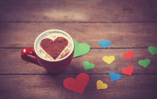 Tasse mit Kaffee- und Herzpapier auf Holztisch. — Stockfoto