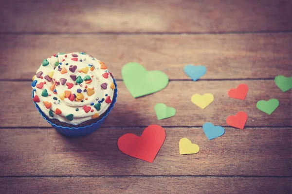 Cupcake and paper hearts on wooden background. — Stock Photo, Image