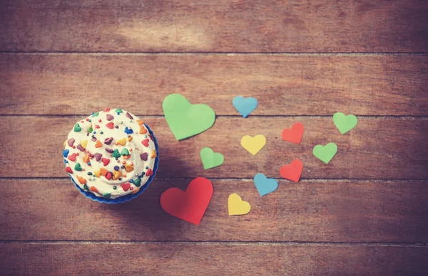 Cupcake and paper hearts on wooden background. — Stock Photo, Image