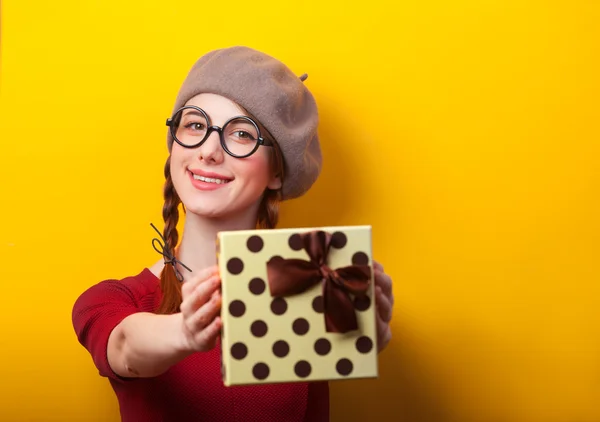 Rödhårig flicka med flätor och present på gul bakgrund. — Stockfoto