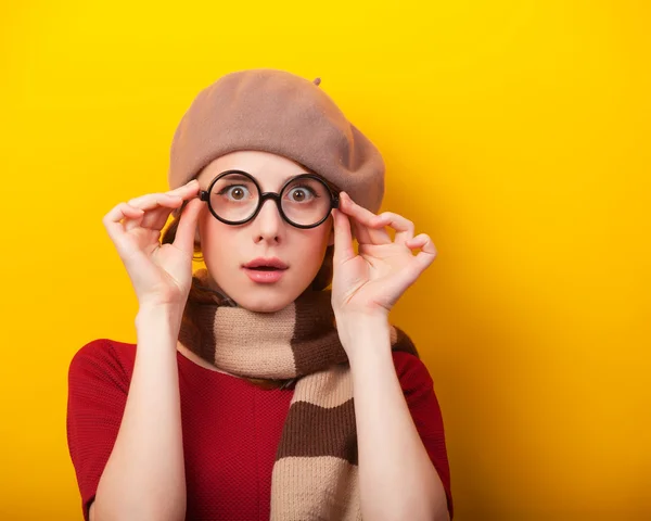 Rödhårig flicka i glasögon och halsduk på gul bakgrund. — Stockfoto