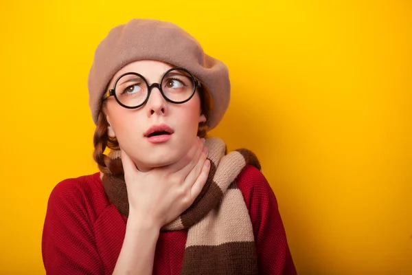 Rothaarige Mädchen mit Brille und Schal auf gelbem Hintergrund. — Stockfoto